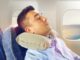 Schlafender Mann mit Kissen im Flugzeug